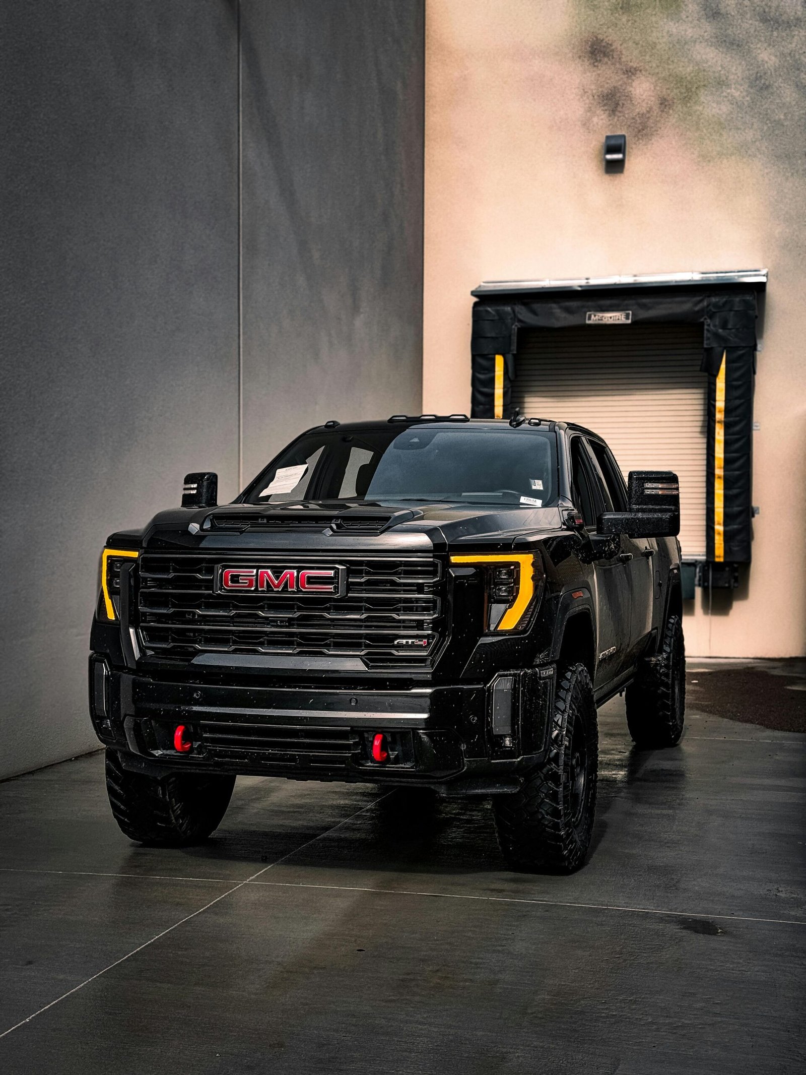 A powerful black GMC truck parked near a loading dock in an industrial area.
